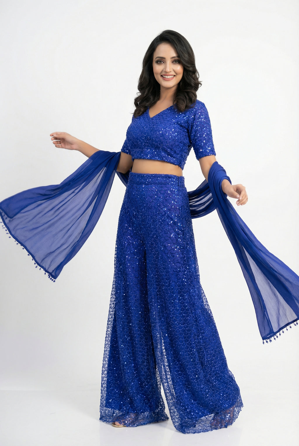 Close-up detail showing the dense, shimmering blue sequin embroidery (sequence work) on the crop top and sharara.