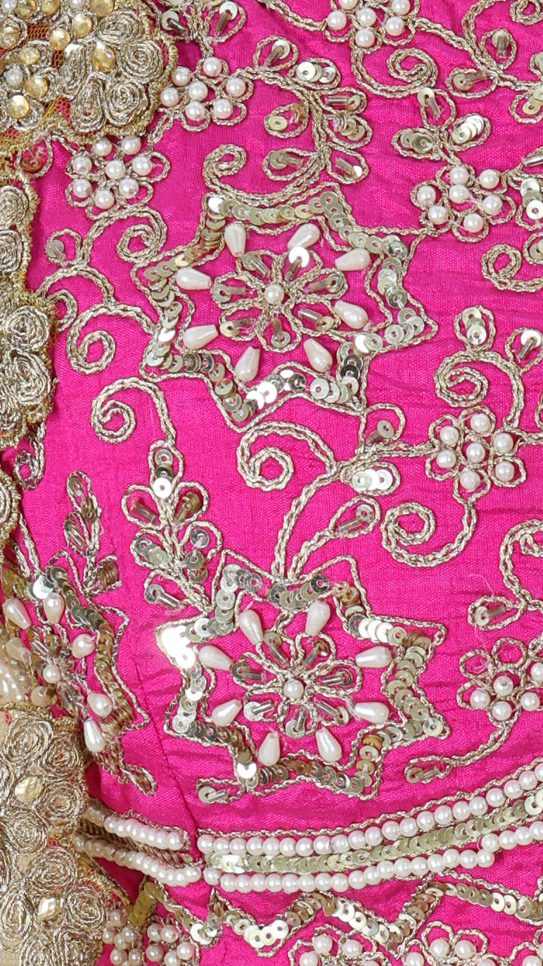 Detail shot of the hot pink sleeveless blouse featuring dense gold embroidery, paired with the multicolor skirt.