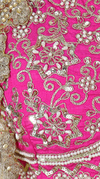 Detail shot of the hot pink sleeveless blouse featuring dense gold embroidery, paired with the multicolor skirt.
