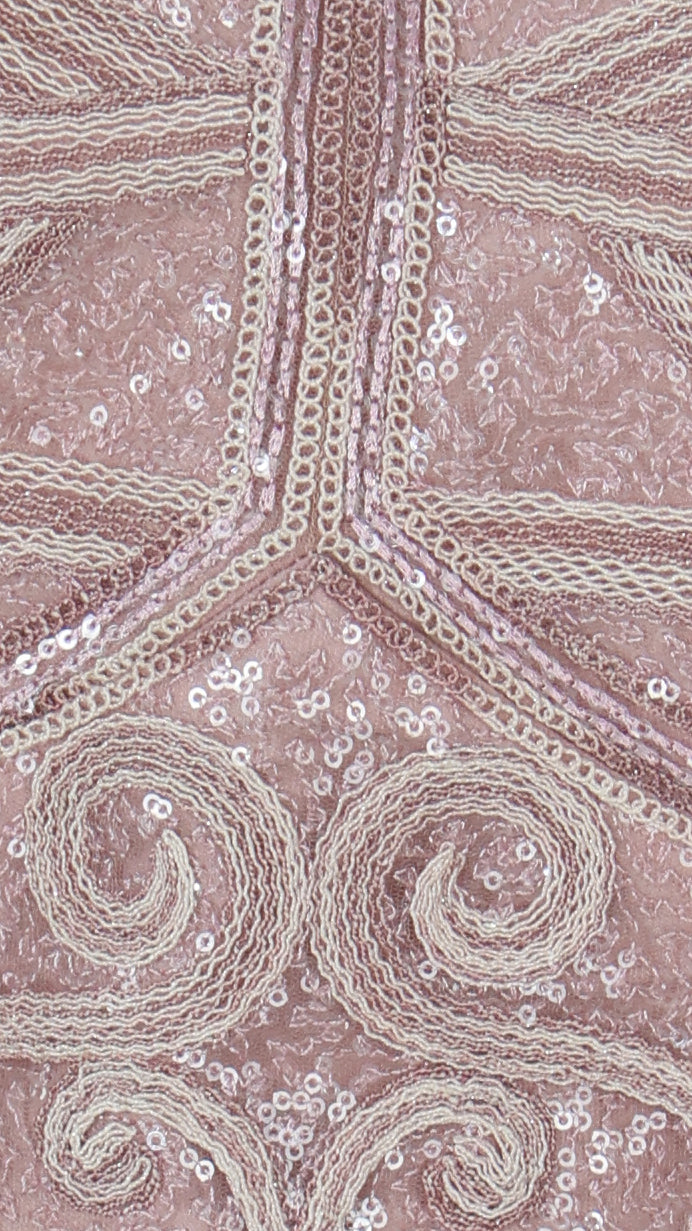 Close-up of pink fabric with intricate white embroidery and sequins