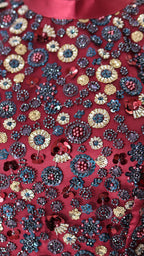 Detail shot showing the smooth, lustrous texture of the maroon satin fabric and the elegant pleats of the drape.