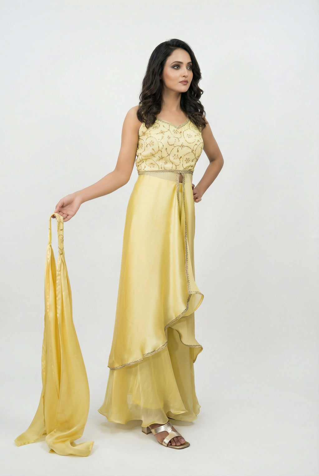 Detail shot showing the shiny, silky texture of the yellow Jimmy Choo fabric and the flowy asymmetrical drape over the pants.