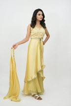 Detail shot showing the shiny, silky texture of the yellow Jimmy Choo fabric and the flowy asymmetrical drape over the pants.