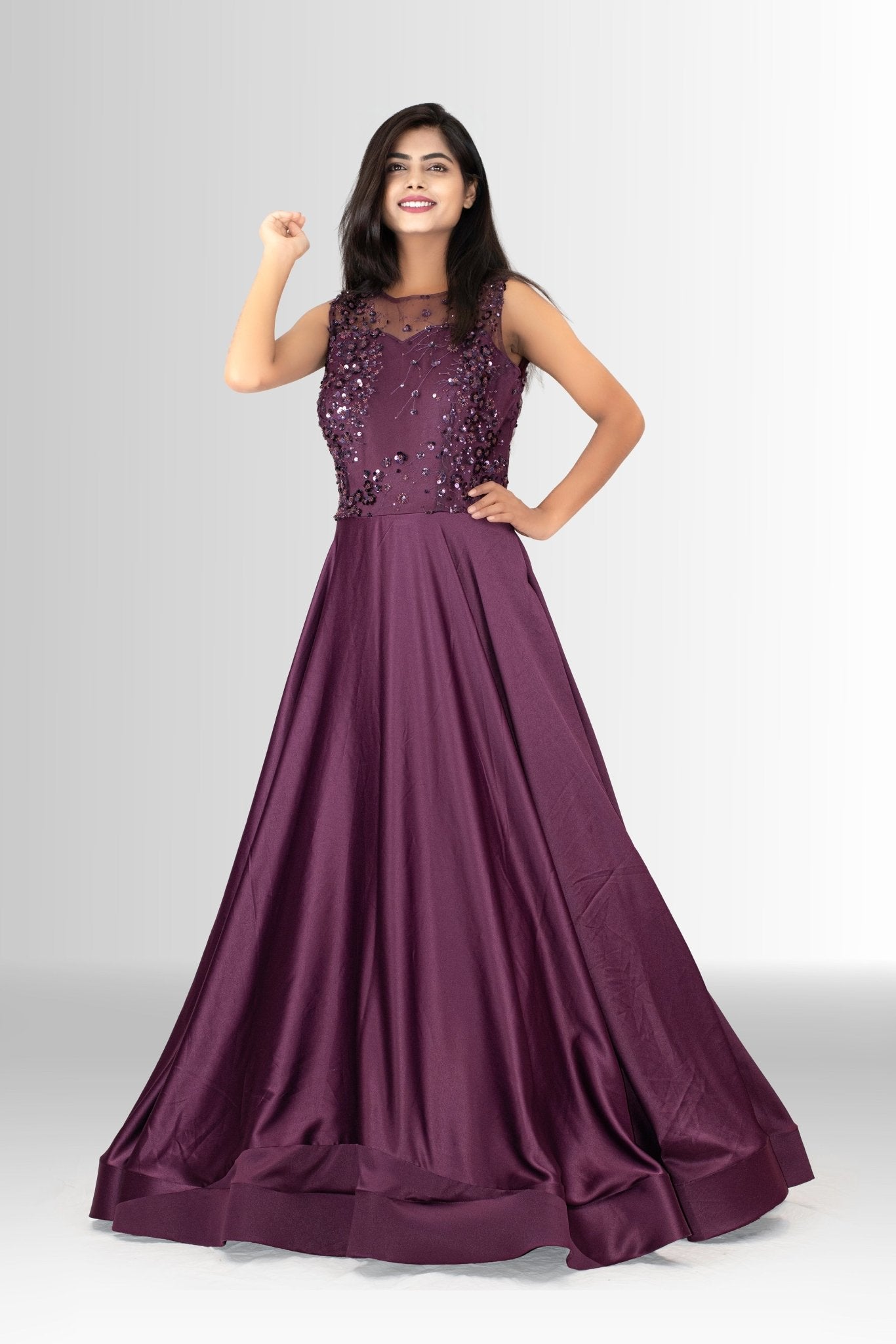A woman models a full-length, sleeveless plum purple evening gown from Rosio House, featuring a heavily embellished sequin bodice and a flowing A-line satin skirt.