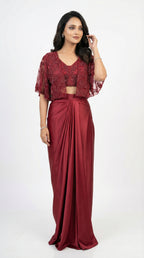 Woman wearing a maroon outfit with a lace top and draped skirt on a white background