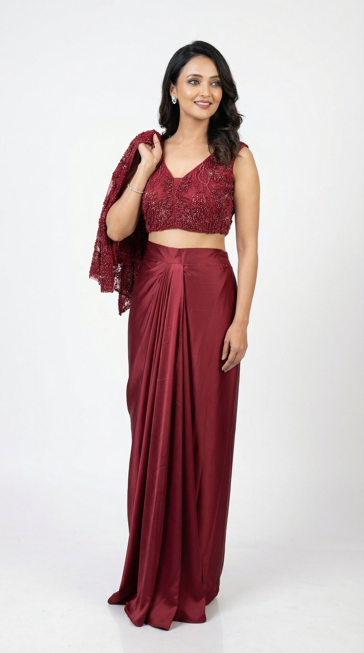 Woman wearing a maroon saree with a matching blouse on a white background
