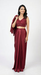 Woman wearing a maroon saree with a matching blouse on a white background