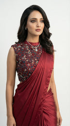 Woman wearing a maroon saree with floral blouse on a white background