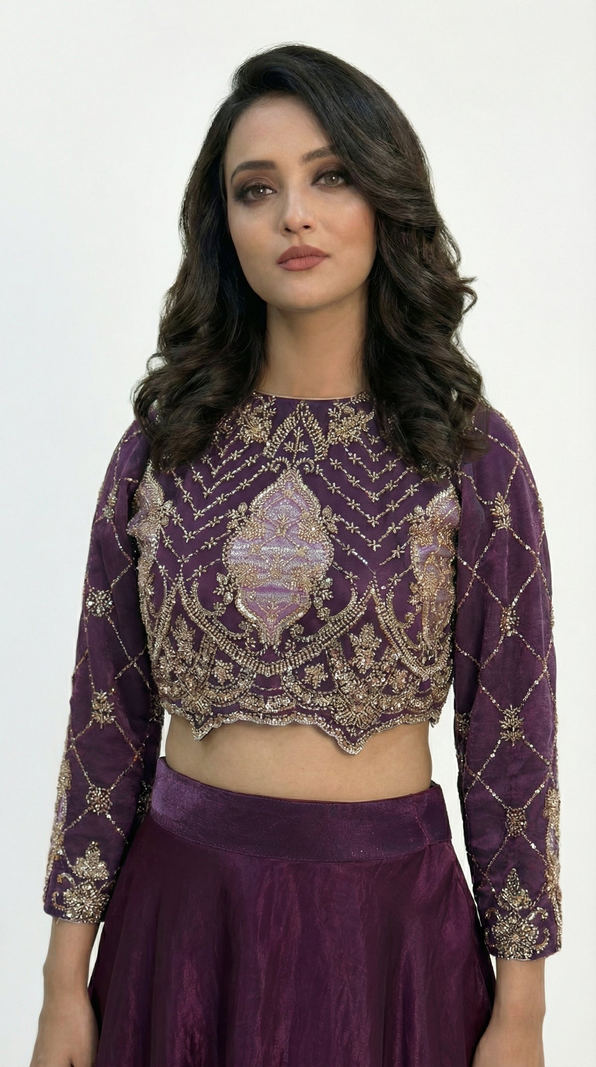 Macro shot of the intricate gold and silver cutdana beadwork in a geometric diamond pattern on the purple blouse.