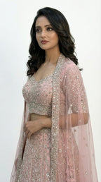 Woman wearing a pink traditional lehenga with a white background