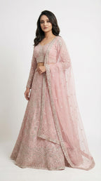 Woman wearing a pink embroidered traditional lehenga on a white background