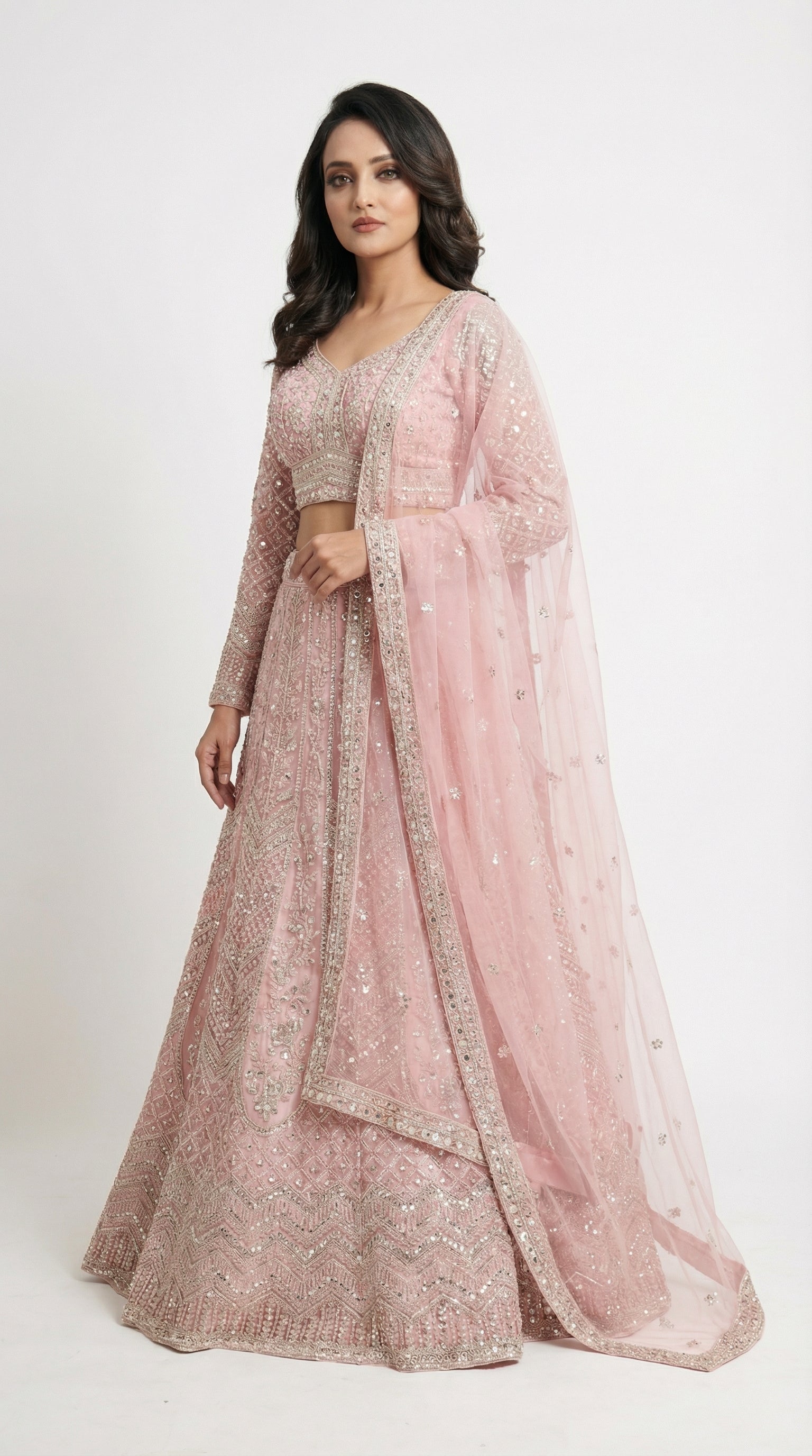 Woman wearing a pink embroidered traditional lehenga on a white background