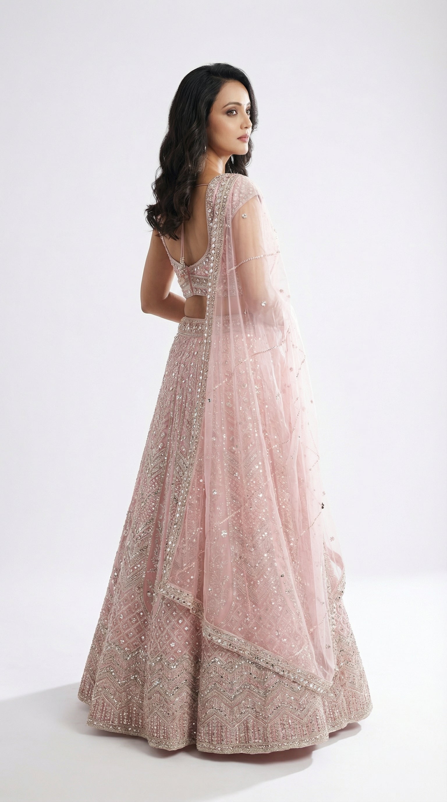 Woman wearing a pink lehenga with a white background