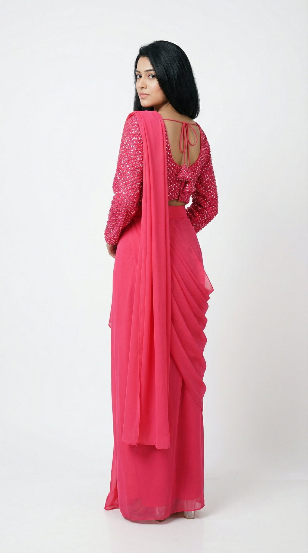 Woman wearing a pink saree with a matching blouse on a white background