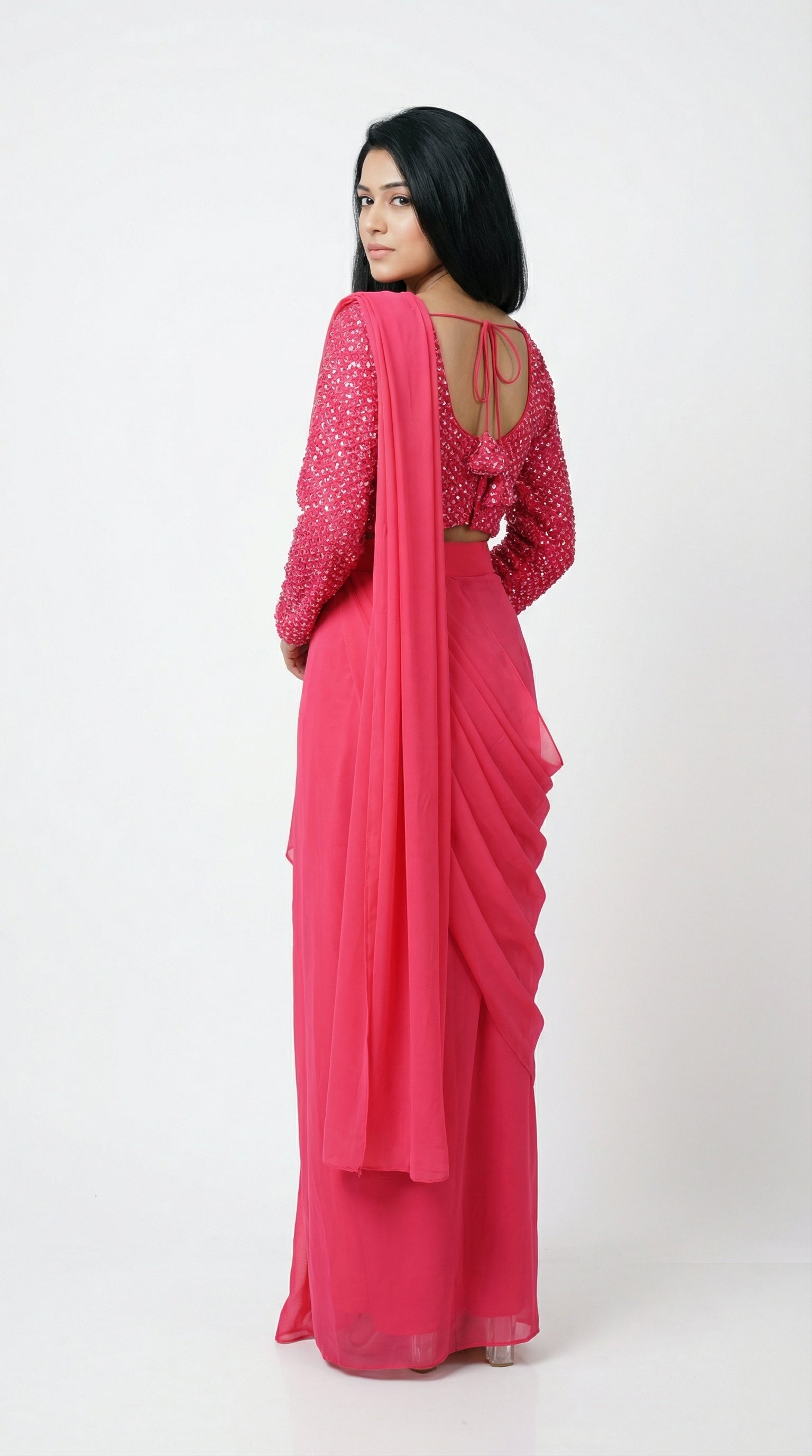 Woman wearing a pink saree with a matching blouse on a white background