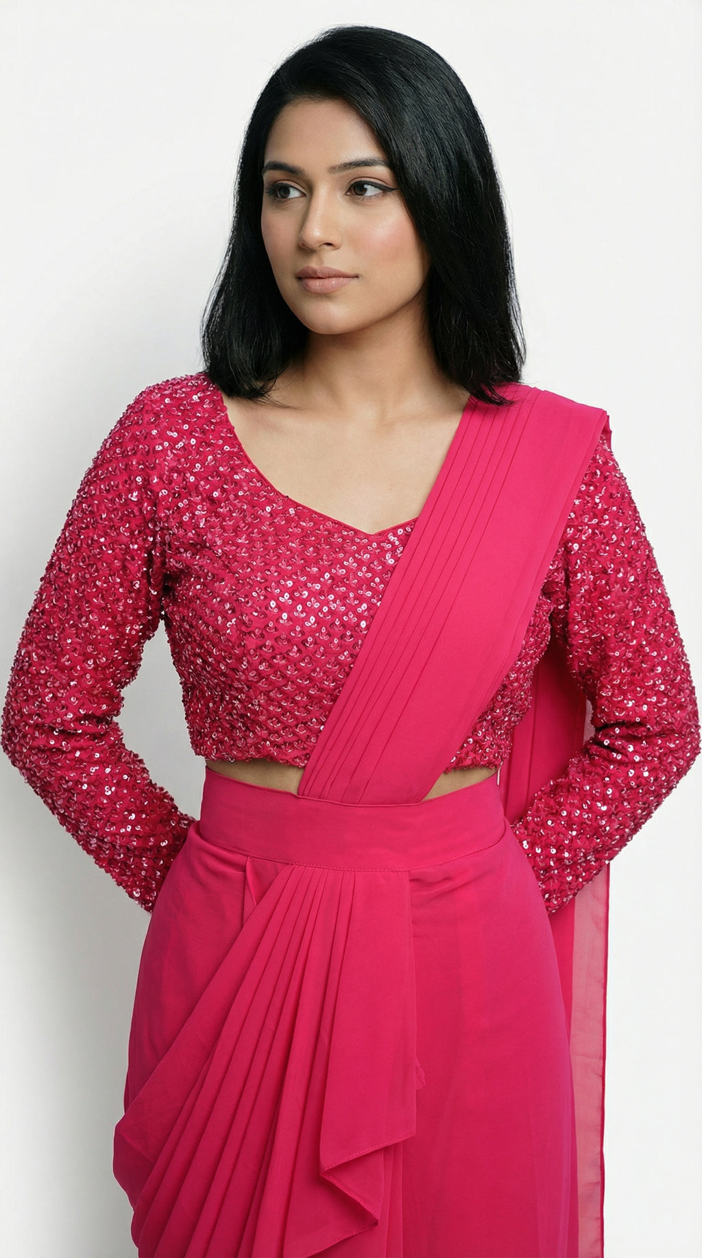 Woman wearing a bright pink saree with a matching blouse on a white background