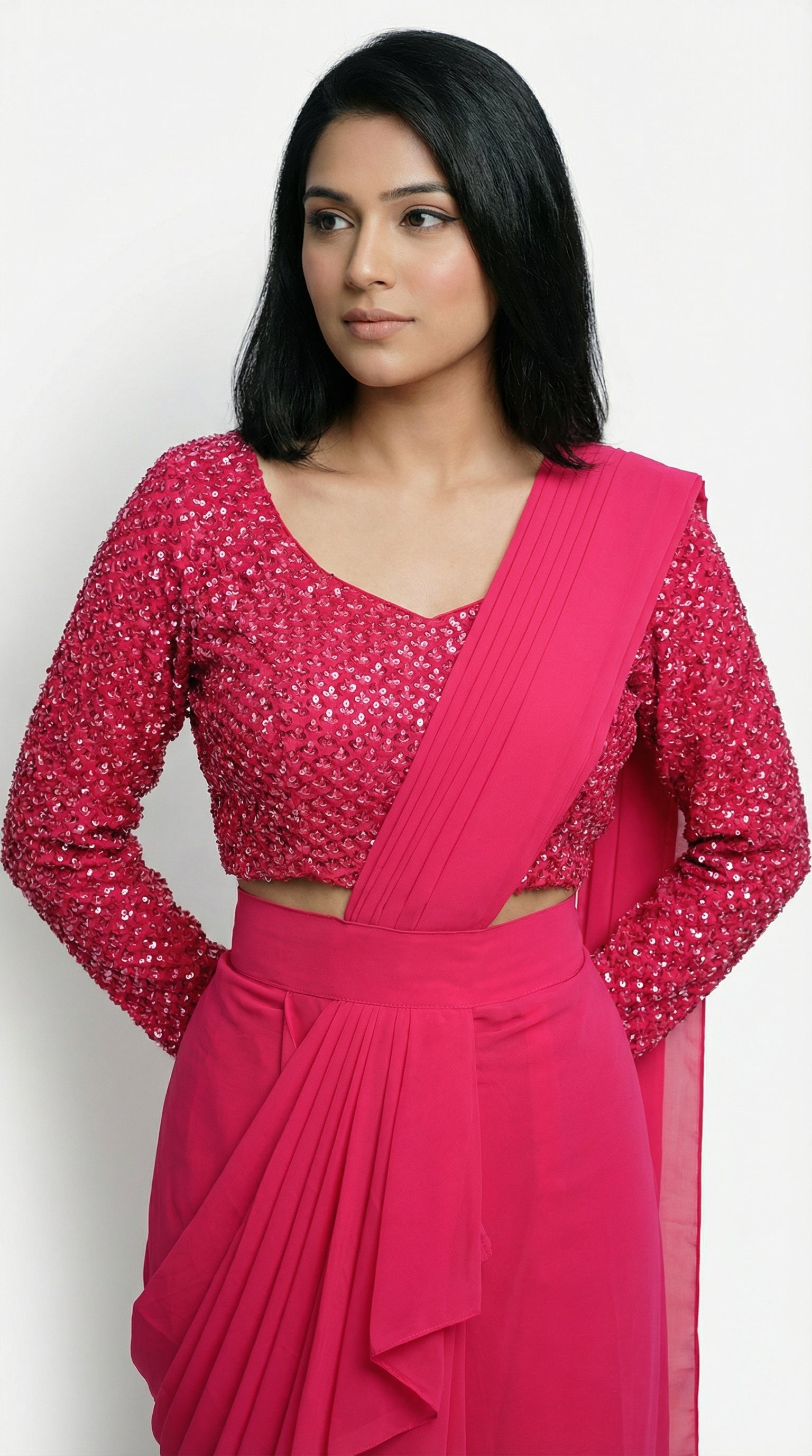 Woman wearing a bright pink saree with a matching blouse on a white background