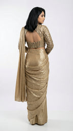 Woman wearing a gold saree with a matching blouse on a white background