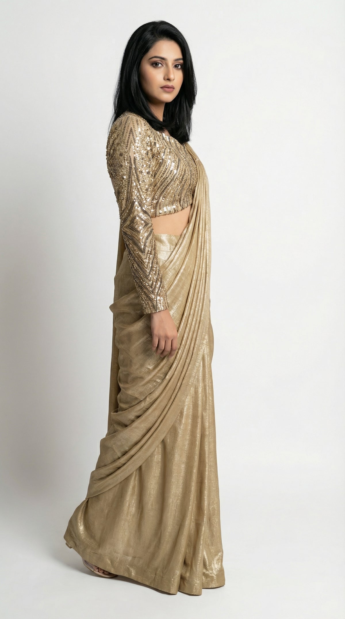 Woman wearing a gold saree with a matching blouse on a white background