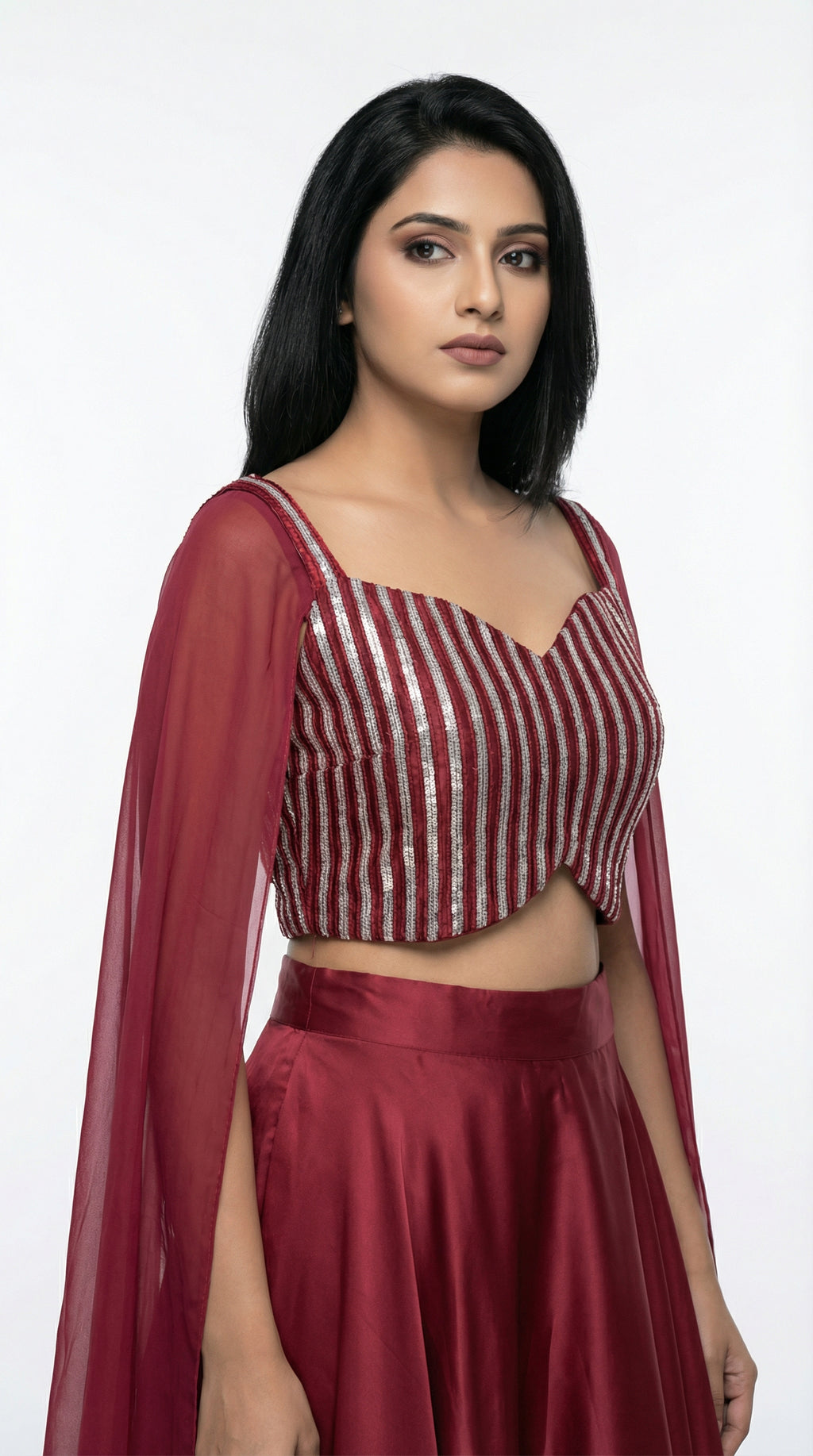 Woman wearing a red crop top handwork and flowy skirt with a white background