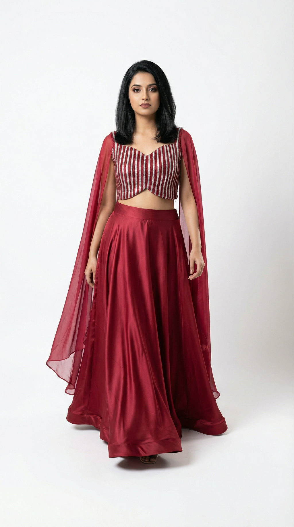 Woman wearing a red crop top handwork and flowy skirt with a white background