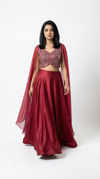 Woman wearing a red crop top handwork and flowy skirt with a white background