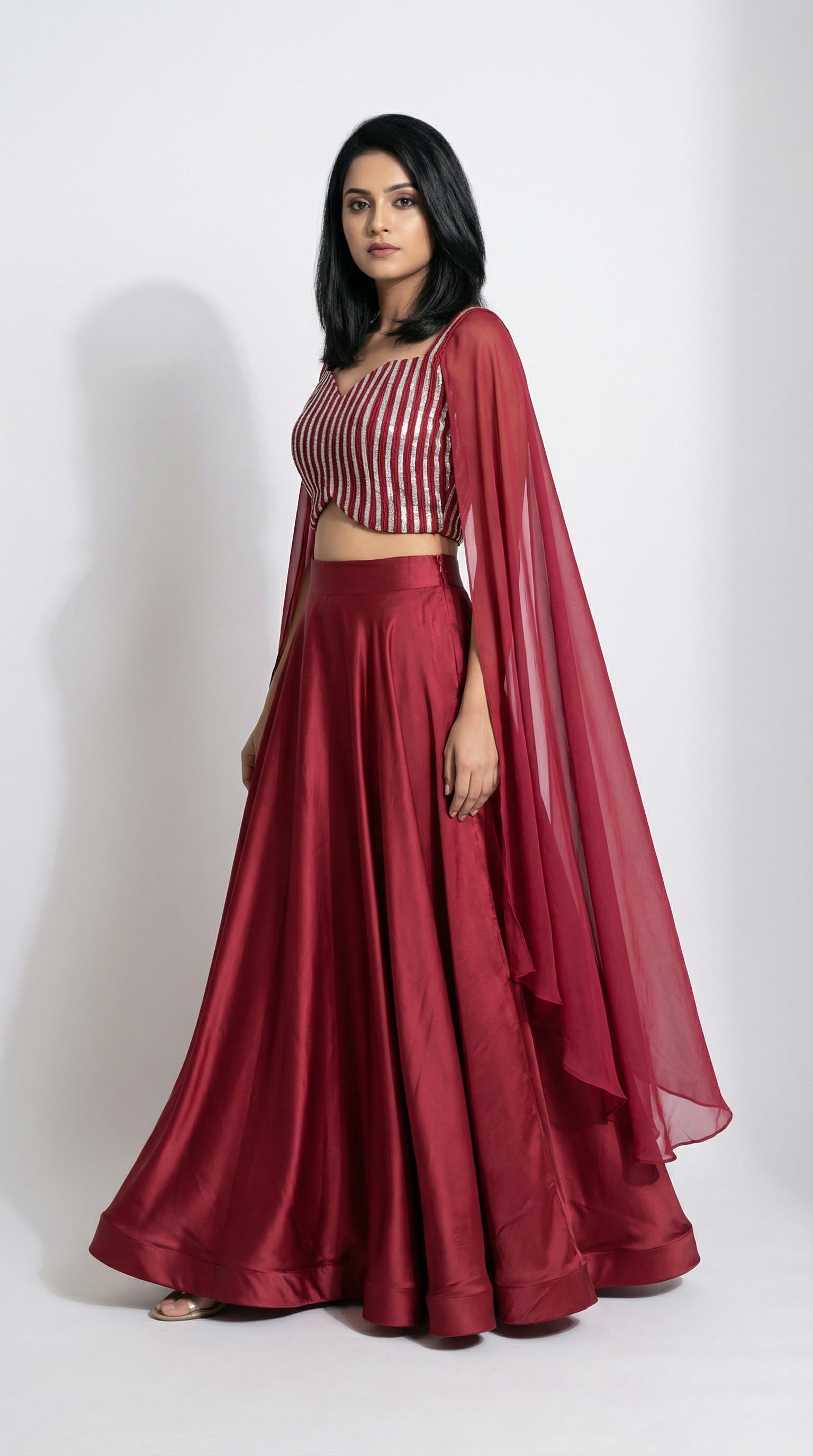 Woman wearing a red crop top handwork and flowy skirt with a white background