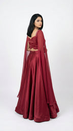 Woman wearing a red crop top handwork and flowy skirt with a white background