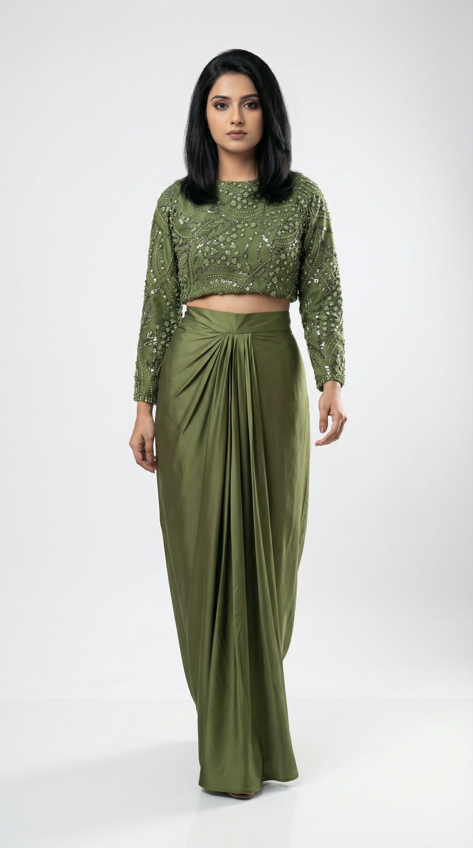 Woman wearing a green outfit with a top and long skirt on a white background