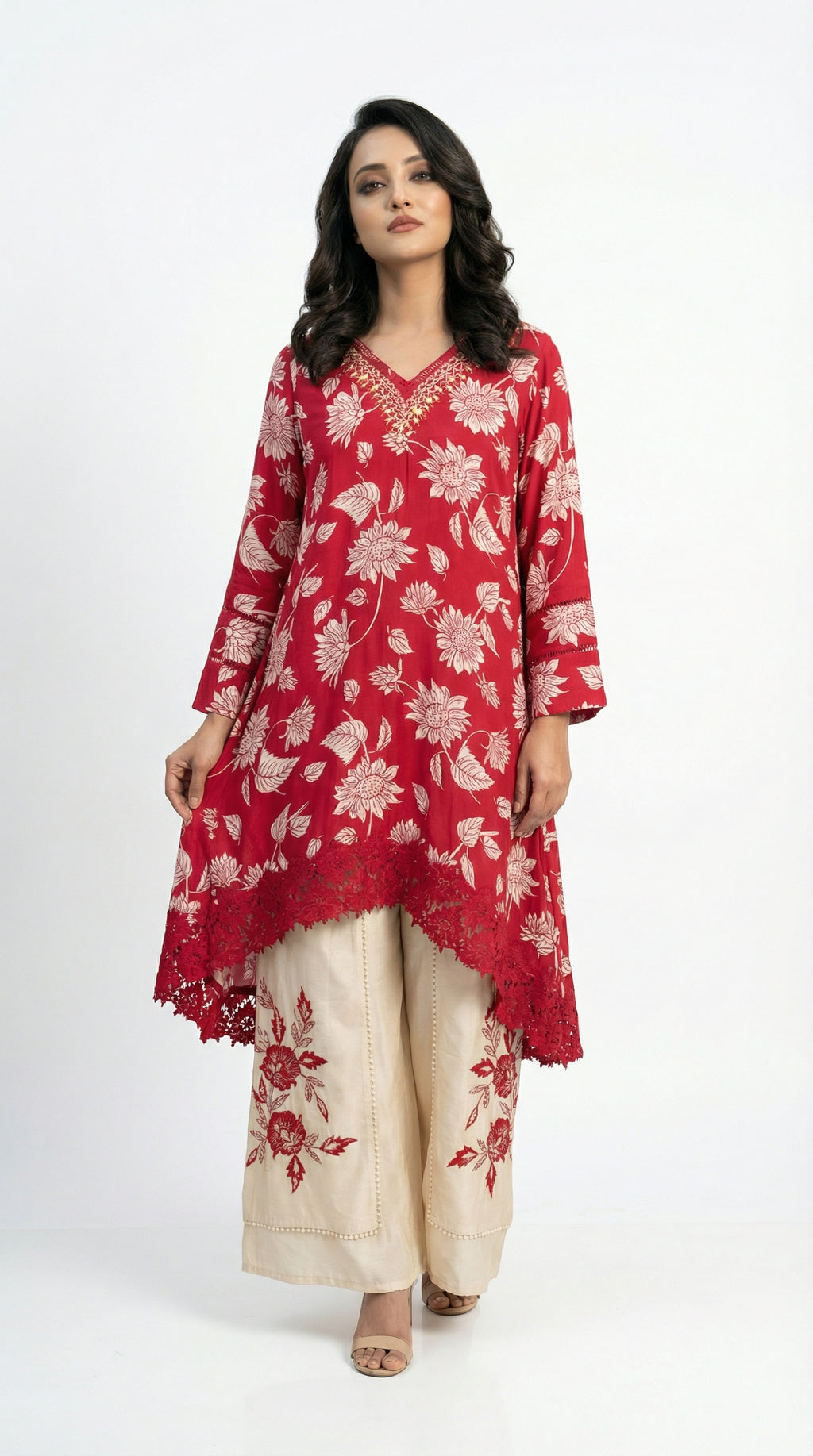 Detail shot of the beige wide-leg palazzo pants showing the large red floral embroidery motifs near the hem.