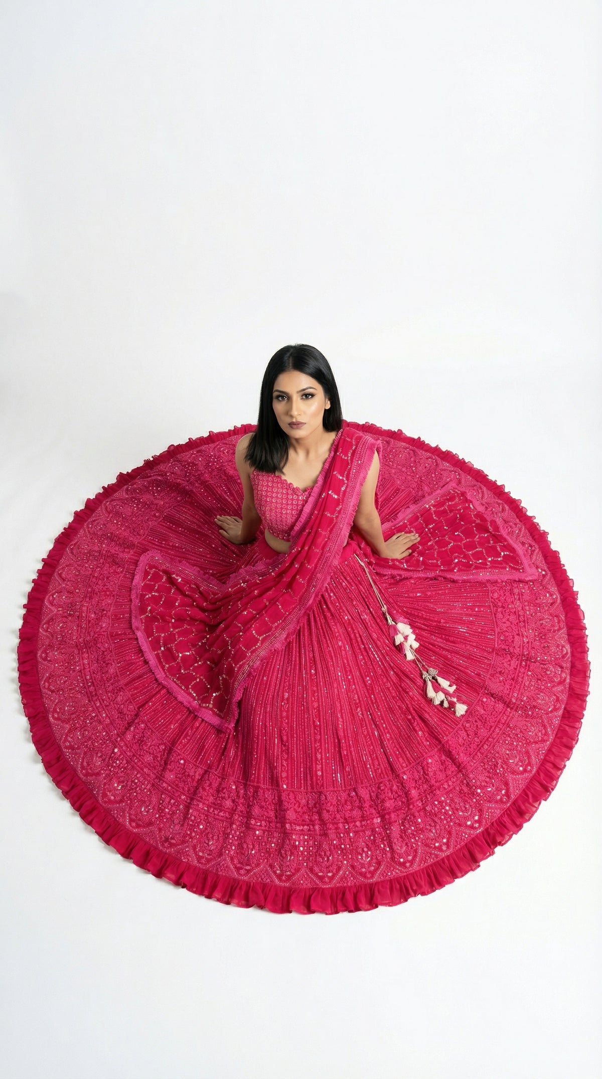 A view of the sheer pink net dupatta draped over the shoulder, highlighting the embroidered sequin border and decorative tassels.