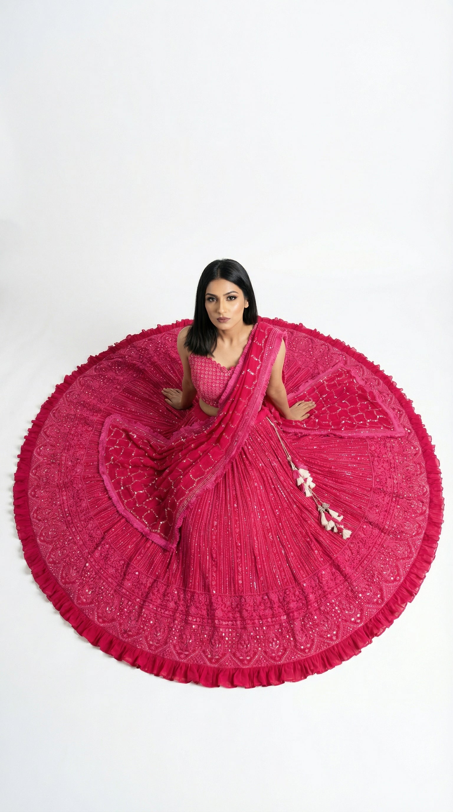 A view of the sheer pink net dupatta draped over the shoulder, highlighting the embroidered sequin border and decorative tassels.