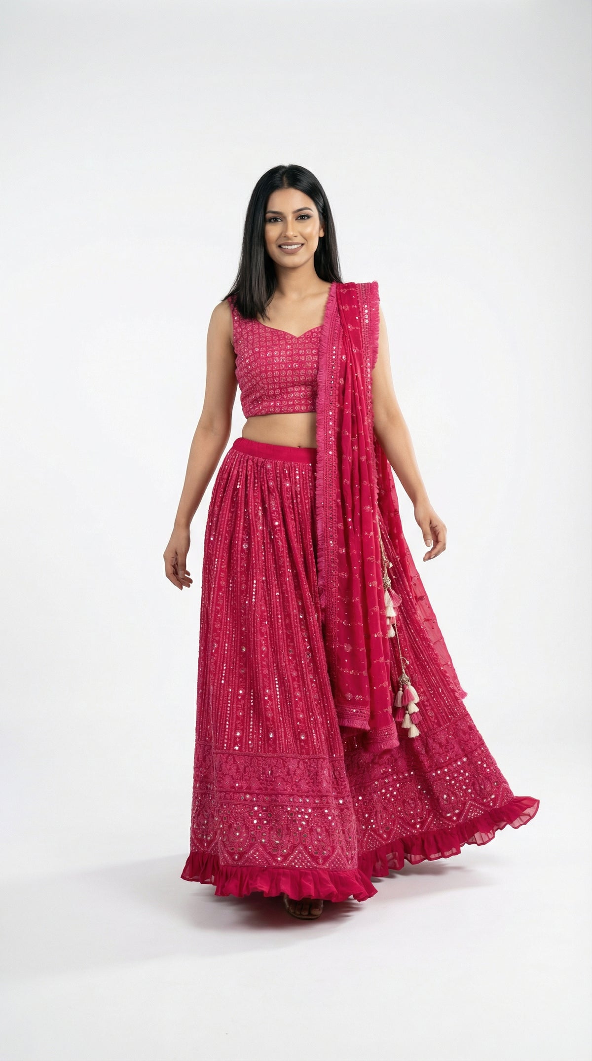 Close-up detail of the pink lehenga skirt showing the dense floral chikankari thread work, sequin highlights, and ruffled hemline.