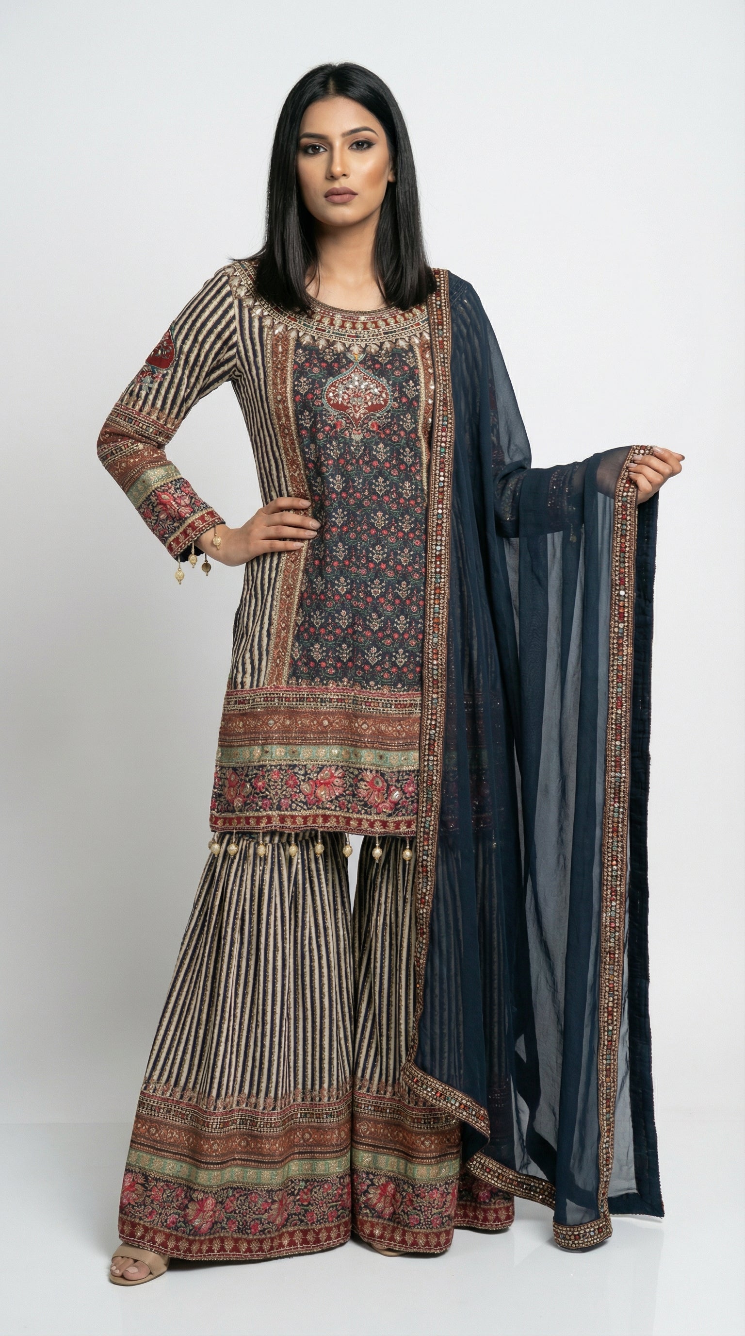 Close-up detail of the hemline of the navy blue kurta, highlighting the intricate floral border print and hanging gold bead tassels.