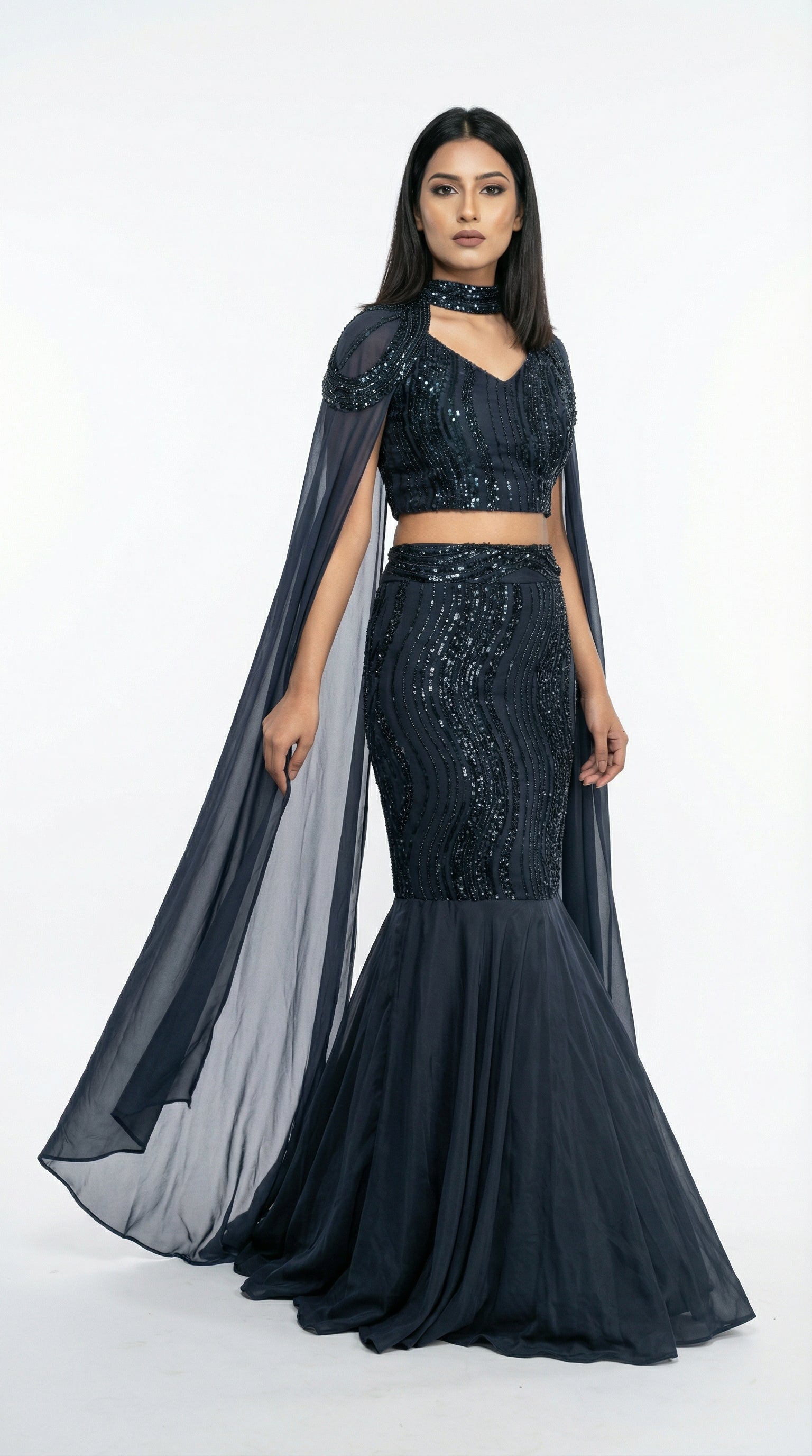 A shot highlighting the dramatic flow of the sheer navy blue cape sleeves attached to the sequin crop top.