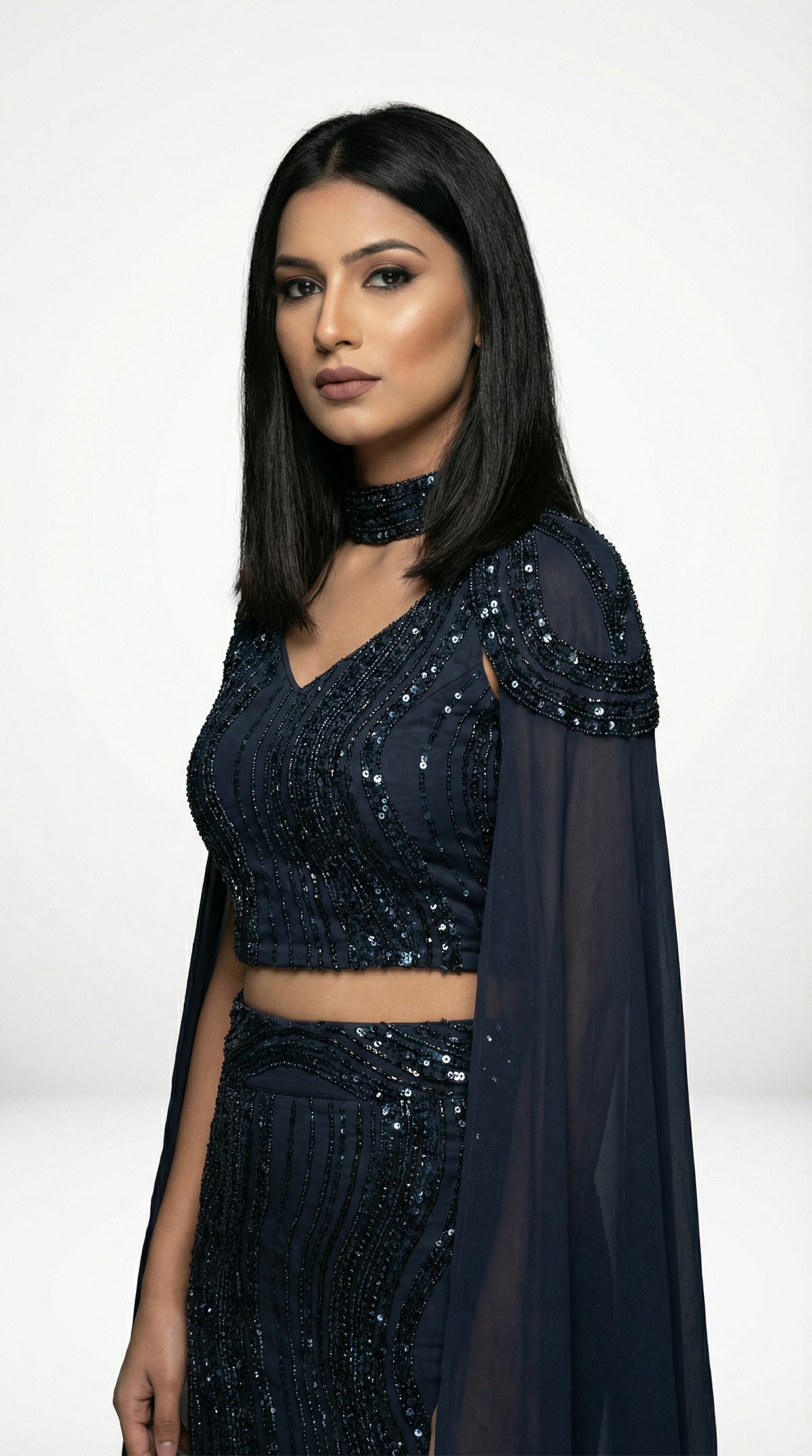 A sophisticated pose showing the sleek silhouette and dramatic cape of the navy blue mermaid lehenga set.