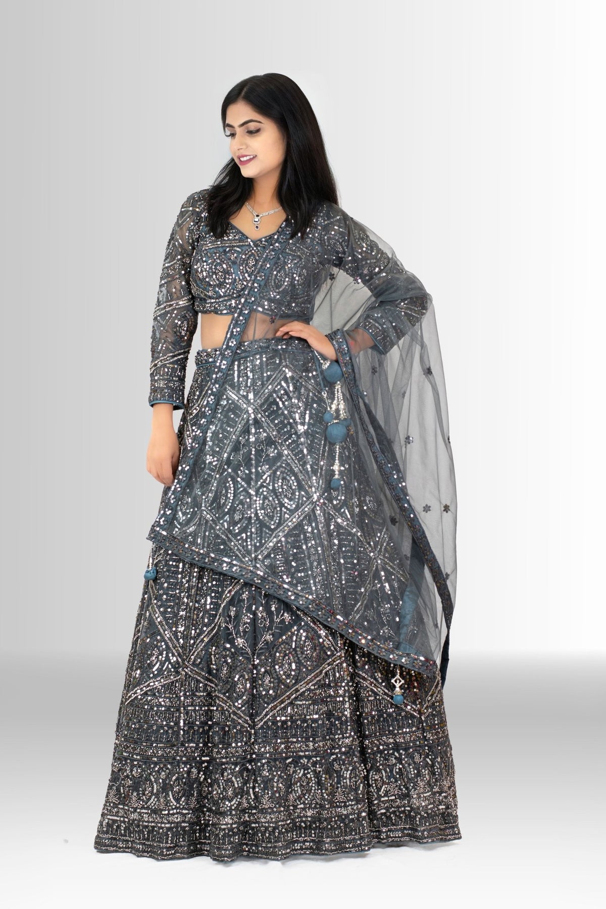 Detailed shot of the voluminous flared lehenga skirt, showcasing the dense geometric sequin work on charcoal grey fabric.