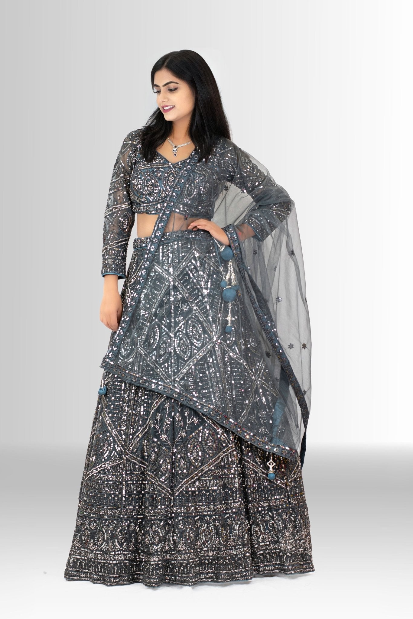 Detailed shot of the voluminous flared lehenga skirt, showcasing the dense geometric sequin work on charcoal grey fabric.