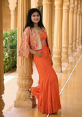 Model wearing a vibrant coral orange Indo western for women by Rosio House, featuring a crop top and an open-front jacket with detailed mirror work. 2