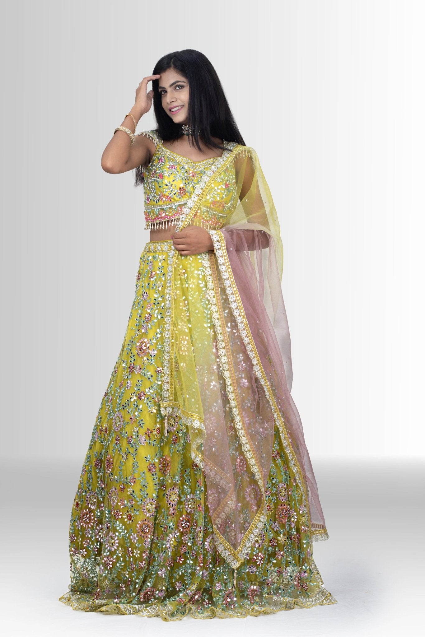 Woman wearing a yellow embroidered traditional outfit with glass work and long duppata 